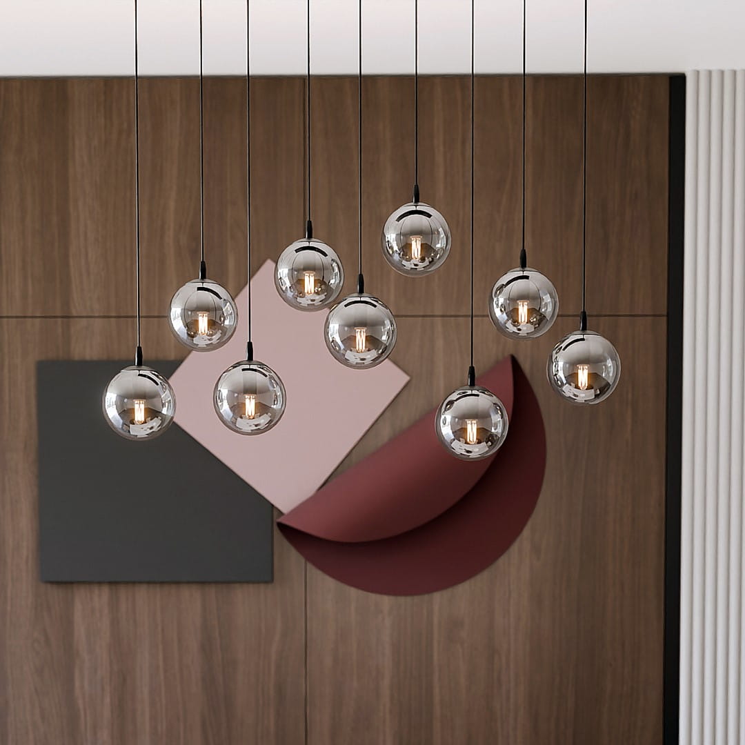 Lampa wisząca Cosmo 9-punktowa w kolorze grafitowym z okrągłymi, szklanymi kloszami. Zawieszona na cienkich linkach, w nowoczesnej aranżacji z tłem w odcieniach brązu i różu. Długość linki pozwala na różne ustawienia wysokości.
