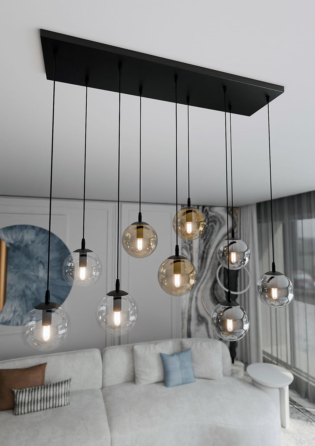 Lampa wisząca Cosmo mix, 9-punktowa, z czarnym stelażem i przezroczystymi oraz szklanymi kulami o różnych odcieniach. Kule zwisają na cienkich przewodach, tworząc efektowną kompozycję nad białą sofą w nowoczesnym wnętrzu.