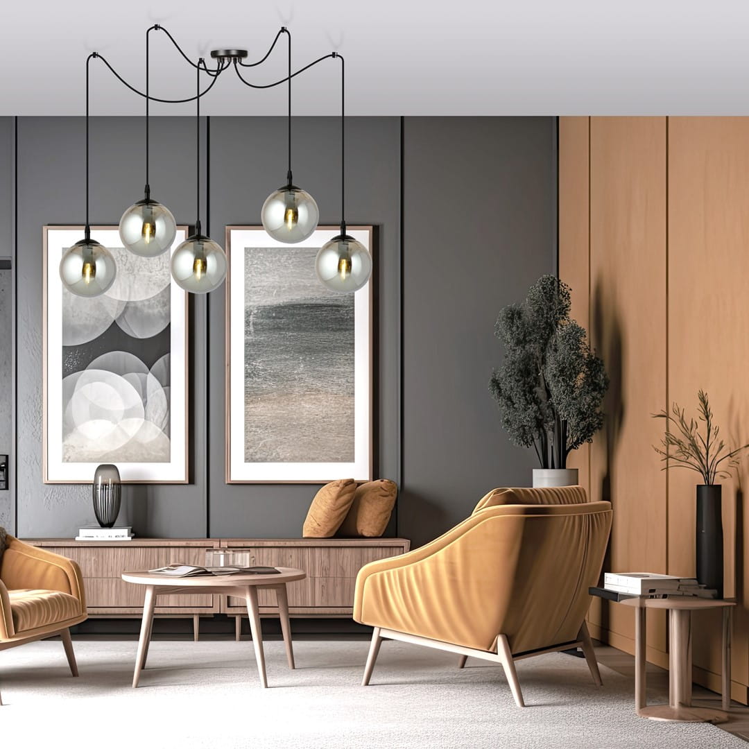 Lampa wisząca Gigi 5-punktowa w kolorze grafitowym z pięcioma szklanymi kloszami, zawieszona na czarnych kablach. Umieszczona w nowoczesnym wnętrzu z beżowymi meblami, obok obrazów na ścianie oraz roślinności.