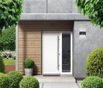 Kinkiet elewacyjny Ortelo 3xLED/6W w kolorze czarnym, zamontowany na ścianie obok białych drzwi. Oświetlenie emitujące światło w górę i dół, umieszczone w nowoczesnym otoczeniu z drewnianymi panelami i zielonymi roślinami.