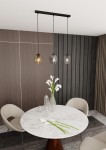 Lampa wisząca Istar mix 3-punktowa, z trzema szklanymi kloszami w odcieniach brązu i szarości, zawieszona na czarnej oprawie. Widoczna w aranżacji nad okrągłym, marmurowym stołem z bukietem białych kwiatów. Tło w odcieniach drewna i tekstyliów.