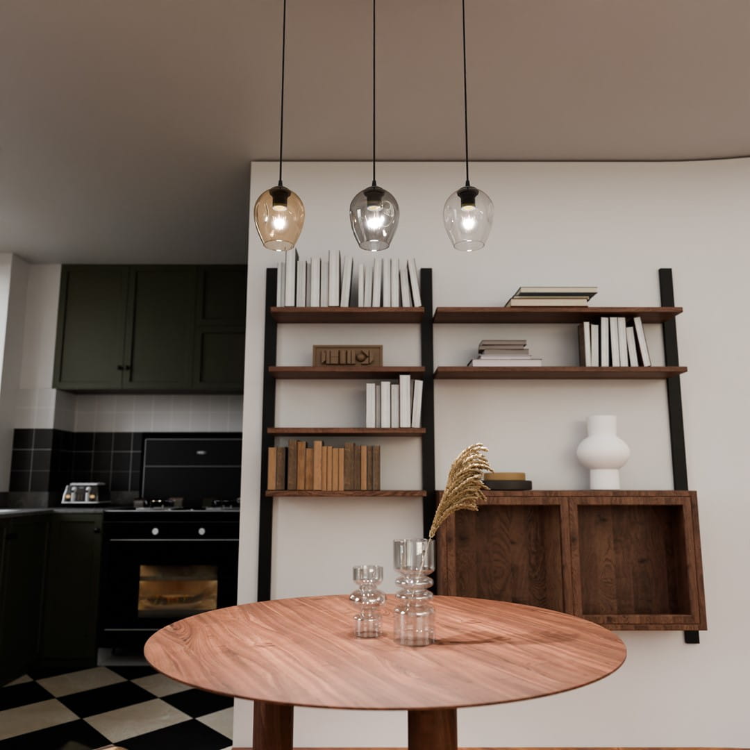 Lampa wisząca Istar mix 3-punktowa z trzema szklanymi kloszami w różnych kolorach (przezroczysty, szary, brązowy) zawieszona nad okrągłym drewnianym stołem. W tle widoczna półka z książkami i dekoracjami oraz kuchnia z ciemnymi szafkami.