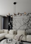 Lampa wisząca Rossi 8-punktowa w kolorze czarnym i grafitowym. Składa się z ośmiu szklanych kloszy w kształcie kul, zawieszonych na cienkich linkach. Ujęcie z góry, w nowoczesnym wnętrzu z jasną sofą i marmurowym stołem. Tło w odcieniach szarości.