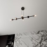 Lampa wisząca Rossi 6-punktowa w kolorze czarnym z transparentnymi kloszami. Ujęcie z góry, produkt wisi na cienkich linkach. Widoczne trzy żarówki, metalowa konstrukcja z okrągłym mocowaniem sufitowym. Tło w jasnych odcieniach z marmurowym wzorem.
