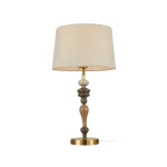 Lampa stołowa Moren z brązowym, antycznym stelażem i jasnobeżowym abażurem. Podstawa z kolorowymi, okrągłymi elementami ceramicznymi. Ustawiona na płaskiej powierzchni, z widocznym kablem. Typ żarówki: 1xE27.