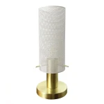 Lampa stołowa Tirana z białym, perforowanym kloszem i złotą podstawą. Klosz cylindryczny, a podstawa okrągła. Widoczne dwa metalowe przyciski po bokach. Produkt ustawiony w pozycji stojącej na jasnym tle.