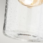 Kinkiet łazienkowy Morvah IP44 w kolorze białym, z przezroczystym kloszem o fakturze z bąbelkami. Klosz ma okrągły kształt, montowany na ścianie, z widocznym miejscem na żarówkę E27. Tło w neutralnym odcieniu, podkreślające detal klosza.