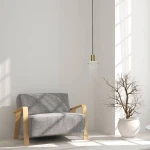 Lampa wisząca Tirana 1xE27 w kolorze złotym i białym, z przezroczystym kloszem, zawieszona na czarnym przewodzie. W tle widoczna szara kanapa z drewnianymi podłokietnikami oraz doniczka z nagim krzewem.