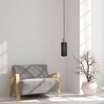 Lampa wisząca Tirana 1xE27 w kolorze złotym i czarnym, z metalowym kloszem w formie siatki, zawieszona na czarnym przewodzie, umieszczona w jasnym wnętrzu obok szarego fotela i doniczki z gałęziami.