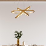Lampa wisząca Eternity z trzema pierścieniami w kolorze naturalnego bambusa i złotym wykończeniu, zawieszona na cienkich żyłkach. Wbudowane oświetlenie LED o mocy 23W, idealna do nowoczesnych wnętrz. Tło w jasnym kolorze.