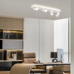 Lampa sufitowa Parma z białym wykończeniem, z zamontowanymi czterema reflektorami GU10 i jednym źródłem LED. Ujęcie z góry w nowoczesnym biurze, z jasnym tłem i meblami w odcieniach drewna.