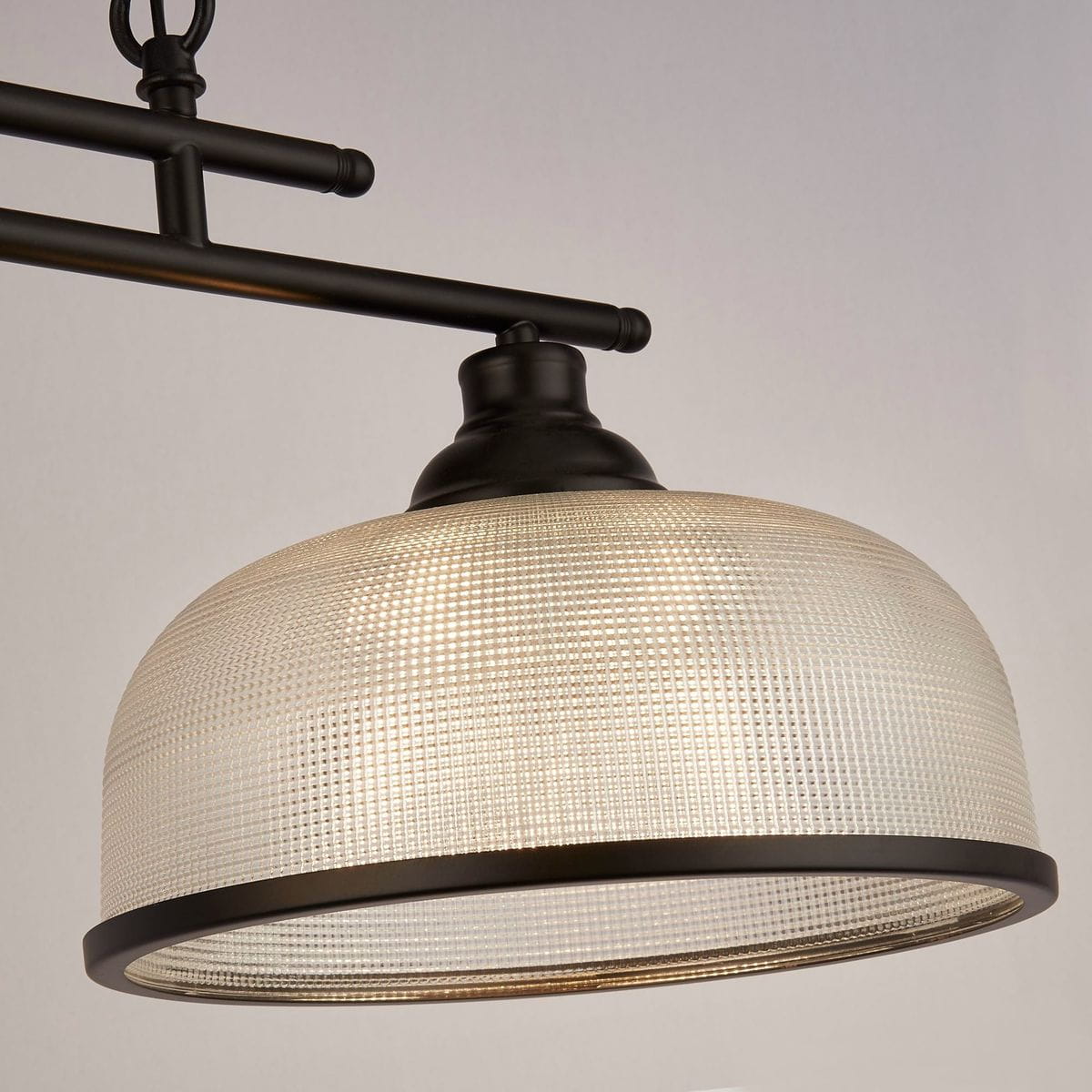 Czarna lampa wisząca Highworth z trzydziestoma miejscami na żarówki E27. Klosz o zaokrąglonym kształcie z teksturowanego szkła, umieszczony na metalowej konstrukcji. Ujęcie z dołu, podkreślające detale klosza i mocowania.