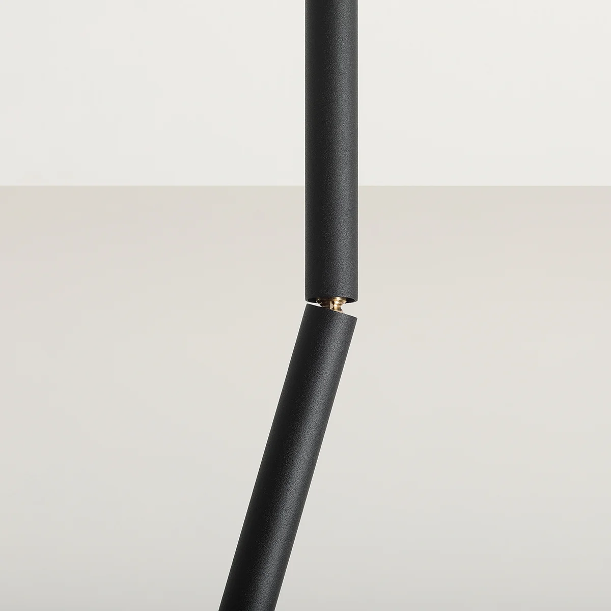 Czarna lampa sufitowa Stick S z jednopunktowym mocowaniem, widok z boku. Składa się z dwóch cylindrycznych segmentów połączonych złotym elementem. Matowa powierzchnia, nowoczesny design, idealna do minimalistycznych wnętrz.