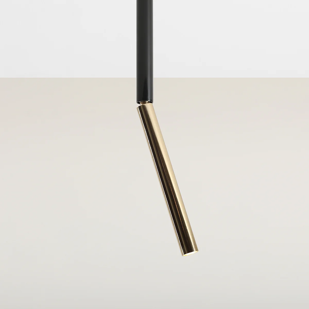 Czarna lampa sufitowa Stick S z złotym akcentem, wisząca w pionie. Wąski, prostokątny korpus z czarnego metalu z końcówką w kolorze złotym. Prosty, nowoczesny design, idealna do minimalistycznych wnętrz.
