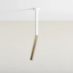Lampa sufitowa Stick S o białym, prostokątnym korpusie i złotym, cylindrycznym kloszu. Ujęcie z dołu, zawieszona pod sufitem. Prosty, nowoczesny design, idealna do minimalistycznych wnętrz.