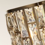 Lampa podłogowa Bijou z antycznym mosiądzu, z kryształowymi detalami. Widok na górną część klosza z prostokątnymi, przezroczystymi kryształami, które odbijają światło, tworząc efekt tęczy.