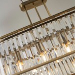 Lampa wisząca Victoria 5xE27 w antycznym mosiądzu. Ozdobiona prostokątnymi, przezroczystymi kryształkami, które odbijają światło. Ujęcie z góry, ukazujące detale konstrukcji i źródła światła. Idealna do eleganckich wnętrz.