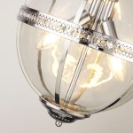 Lampa wisząca Coronet 3xE14 w chromowanym wykończeniu. Okrągła, szklana kula z metalową obręczą z wzorem. Widoczne trzy żarówki E14 w środku. Pozycja w zbliżeniu, ukazująca detale konstrukcji i przezroczystość materiału.