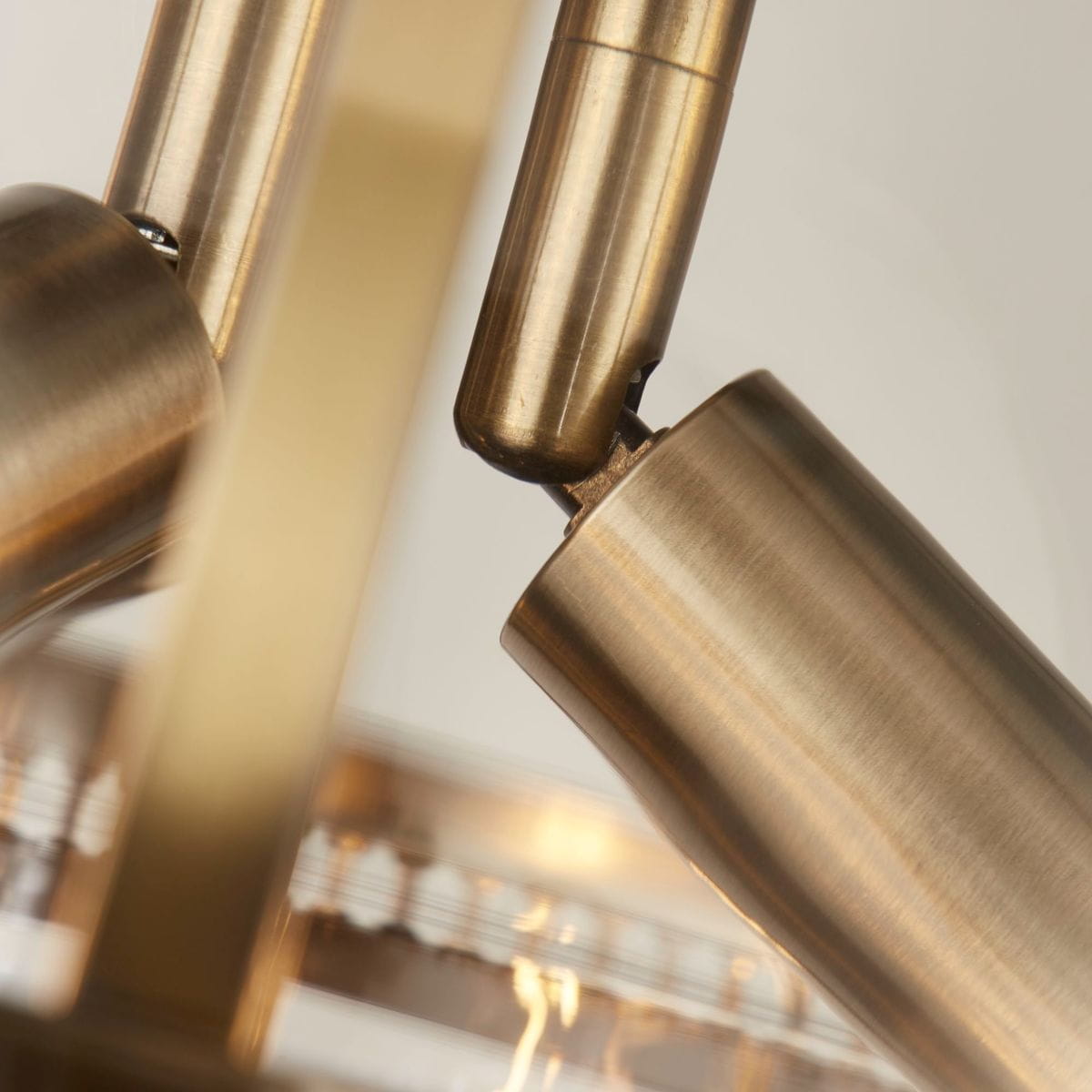 Lampa wisząca Coronet w antycznym mosiądzu z trzema gniazdami E14. Ujęcie zbliżeniowe na detale mocowania i teksturę metalowych elementów, ukazujące elegancki design i wykończenie.