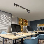 Czarna lampa sufitowa Perugia z pilotem, z czterema oprawami na żarówki GU10 i jedną LED, zamontowana na suficie. Oświetlenie w nowoczesnym biurze, z widocznymi komputerami i jasnym tłem.