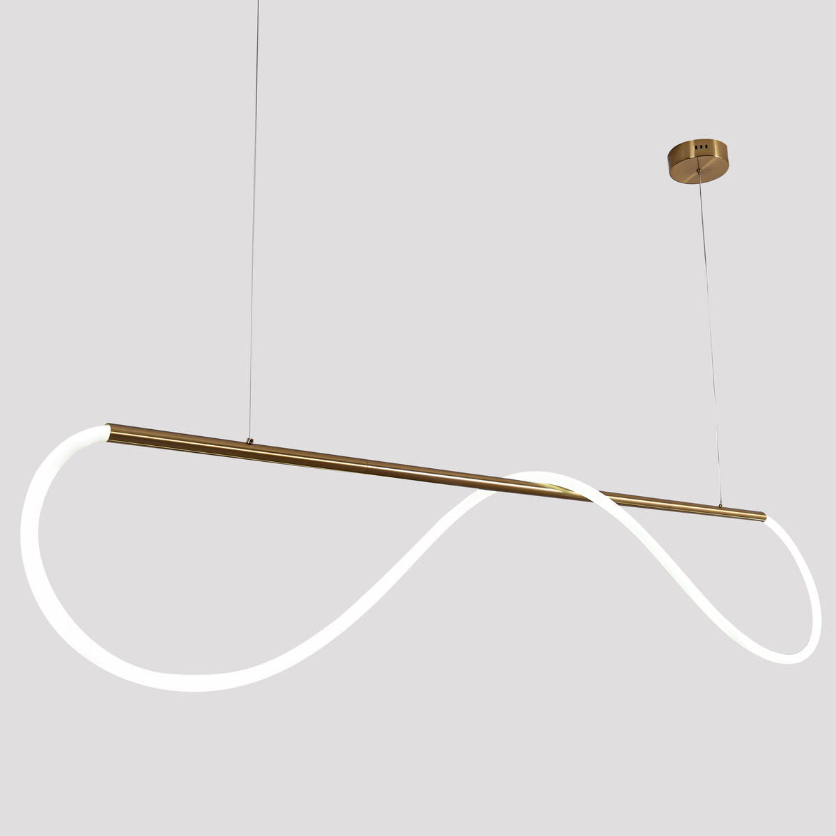 Lampa wisząca Meleca LP-2345/1P w kolorze złotym. Posiada minimalistyczny kształt w formie fali z białym światłem LED. Zawieszona na cienkich linkach, kontrolowana za pomocą pilota. Tło szare, proste.
