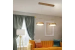 Lampa wisząca Thea z dwoma okrągłymi źródłami światła LED, złote metalowe klosze na przezroczystych zawieszkach. Zawieszona nad pomarańczową sofą, w tle zielone zasłony i białe ściany z dekoracją.