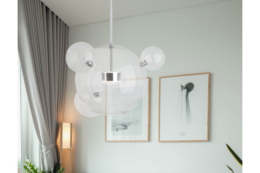 Lampa wisząca Multiverse 1xLED/10W w chromie, z przezroczystymi kloszami w kształcie kul, zawieszona na cienkim stalowym przewodzie. Tło z jasnymi zasłonami i minimalistycznymi obrazami na ścianie.