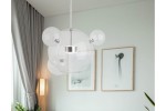 Lampa wisząca Multiverse 1xLED/10W w chromie, z przezroczystymi kloszami w kształcie kul, zawieszona na cienkim stalowym przewodzie. Tło z jasnymi zasłonami i minimalistycznymi obrazami na ścianie.