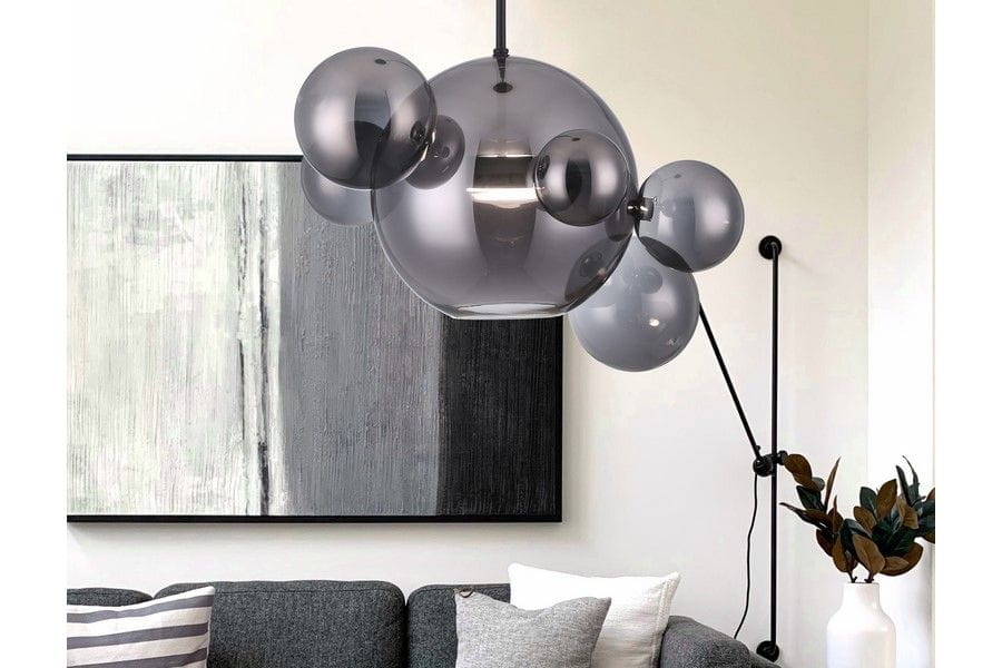 Lampa wisząca Multiverse w kolorze czarnym, z pojedynczym źródłem LED o mocy 10W. Okrągła, szklana konstrukcja z dekoracyjnymi kulami w różnych rozmiarach. Zawieszona w nowoczesnym wnętrzu nad szaro-skalnym obrazem i kanapą.
