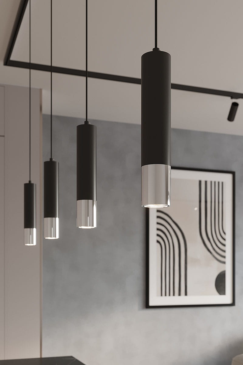 Lampa wisząca Loopez 1xGU10 w czarnym kolorze z chromowanym wykończeniem. Posiada cylindryczny kształt z połyskującym elementem u dołu. Powieszona na cienkich przewodach, w ustawieniu wiszącym, w nowoczesnym wnętrzu z abstrakcyjnym obrazem w tle.