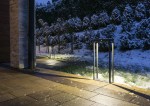 Lampa stojąca ogrodowa Arma Solar H50 w kolorze ciemnego popielu, z jedną żarówką LED o mocy 2W. Ujęcie z boku, lampa ustawiona na płaskim podłożu, oświetlająca ścieżkę, w tle śnieżne krzewy i trawa.