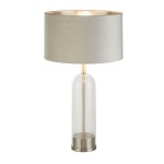 Lampa stołowa Oxford z kloszem w kolorze szaro-beżowym i satynowoniklową podstawą. Szklana, cylindryczna podstawa z metalowym wykończeniem. Klosz o złotej wewnętrznej stronie, stojący na płaskiej powierzchni, w stylowym, nowoczesnym designie.