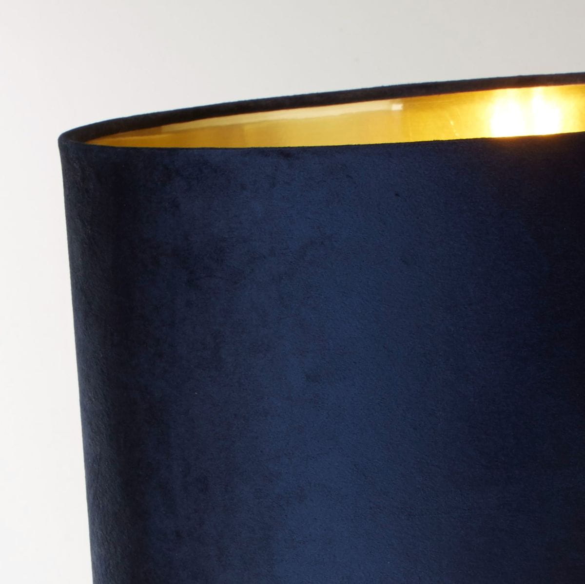 Lampa stołowa Scarborough w granatowym kolorze z mosiężnym wykończeniem. Abażur ma matową, teksturowaną powierzchnię, z widocznym wnętrzem w kolorze złotym, co podkreśla elegancki design. Ujęcie w zbliżeniu na detal abażuru.
