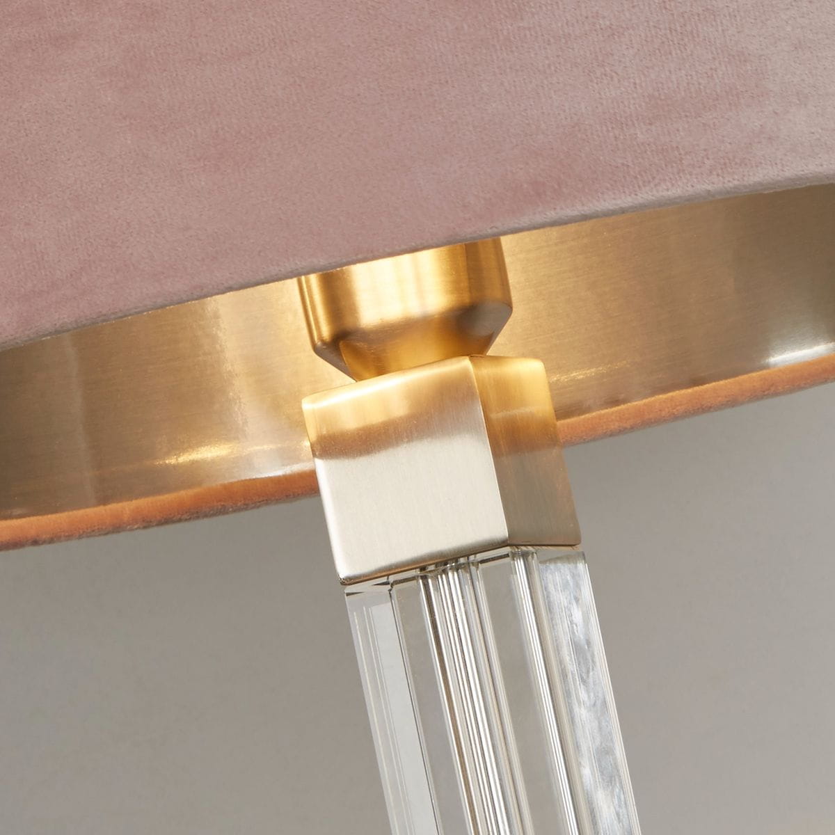 Lampa stołowa Scarborough z kloszem w różowym kolorze z weluru, z metalowym wykończeniem w satynowym niklu. U podstawy widoczne przezroczyste elementy z tworzywa, które tworzą elegancki efekt wizualny. Kąt ujęcia zbliżony na detale.