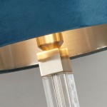 Lampa stołowa Scarborough z kloszem w kolorze turkusowym, wykończona satynowym niklem. Widoczny detal podstawy z przezroczystego materiału oraz złotym akcentem. Ujęcie zbliżeniowe na połączenie klosza z podstawą.