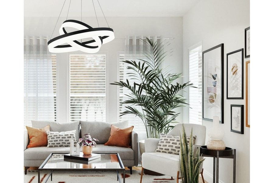 Lampa wisząca Cornelia 2xLED/60W w kolorze czarnym, o nowoczesnym, spiralnym kształcie. Zawieszona w jasnym wnętrzu z roślinnością i sofą, tworzy elegancką aranżację. Widoczne detale to białe elementy dekoracyjne oraz stylowe poduszki na kanapie.