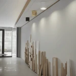 Lampa sufitowa Luna w kolorze czarnym, model tuba 1xGU10/IP65, zamontowana na białym suficie. W tle widoczne inne lampy oraz dekoracyjne elementy drewniane na ścianie. Oświetlenie skierowane na ścianę, tworząc nowoczesną aranżację wnętrza.