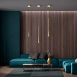 Lampa wisząca Elysia w kolorze złotym z jedną diodą LED 6W, zawieszona w trzech smukłych oprawach, umieszczona nad niebieską sofą w nowoczesnym wnętrzu z drewnianą ścianą w tle.