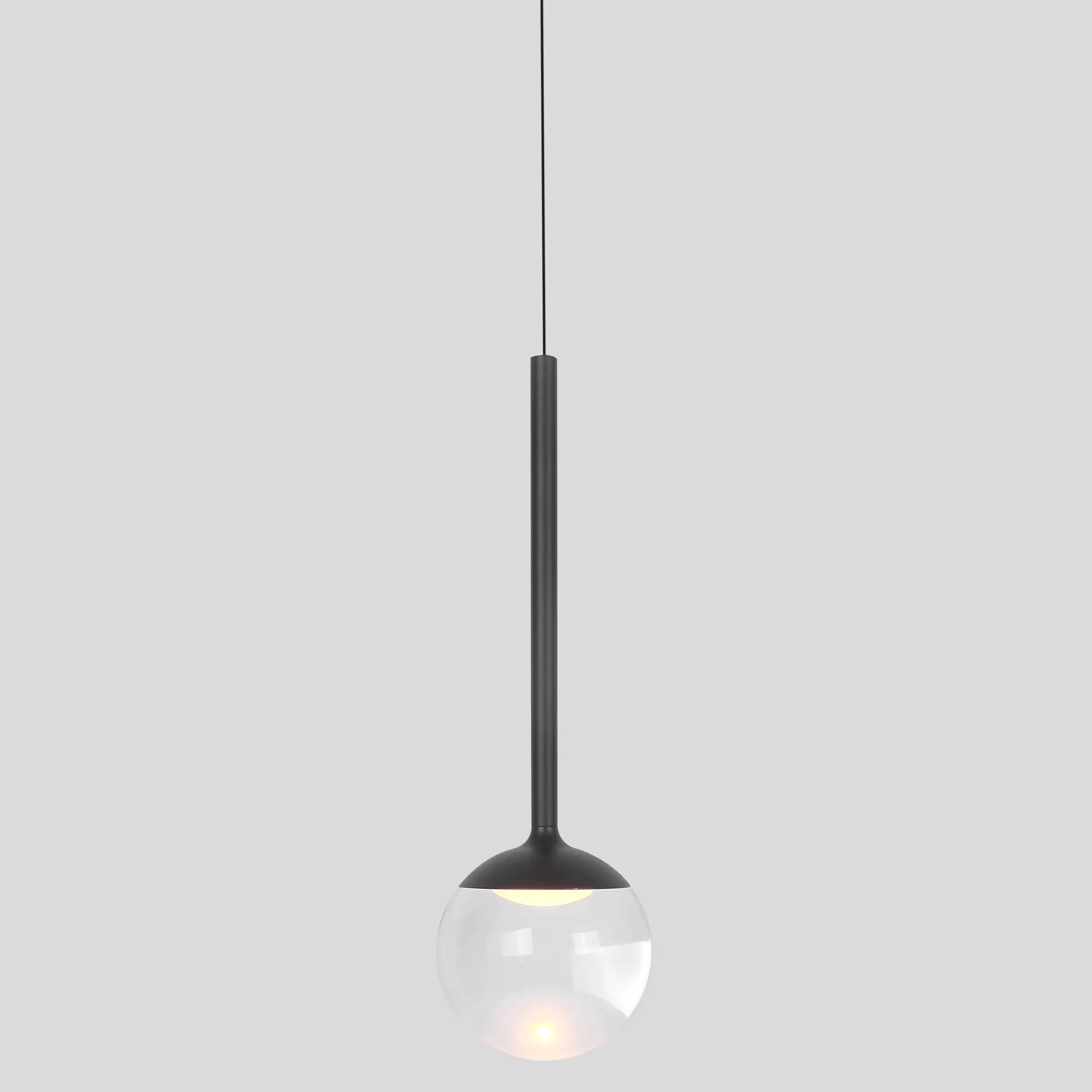 Lampa wisząca Orra z czarnym metalowym uchwytem i przezroczystą kulistą osłoną. Zawieszona na cienkim kablu, z widocznym źródłem światła LED 6W. Prosty, nowoczesny design idealny do różnych wnętrz.