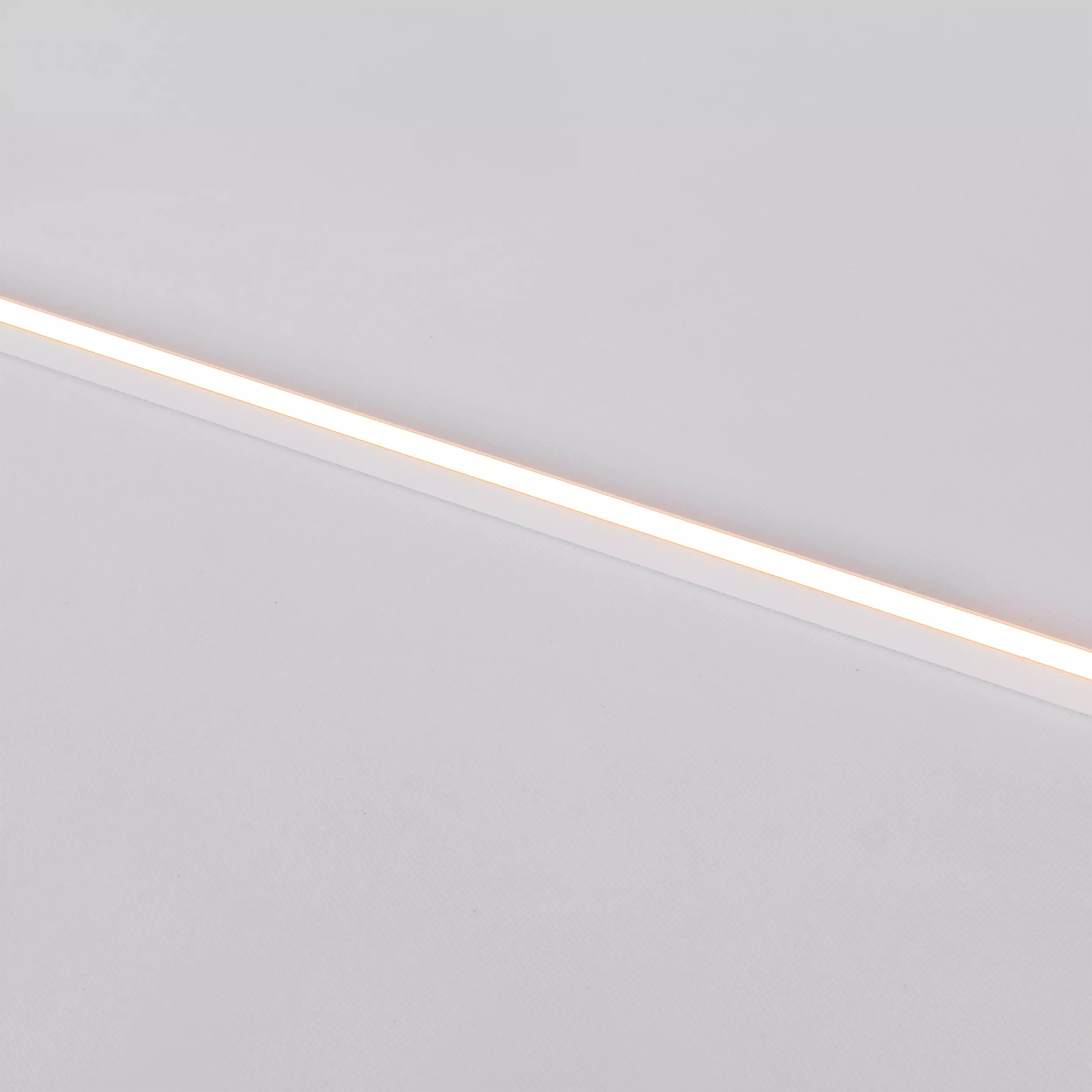 Kinkiet Chloe 85 w kolorze białym, z jedną diodą LED o mocy 11W i temperaturze barwowej 3000K. Produkt leży na jasnym tle, ukazując prostą, minimalistyczną formę. Zbliżenie na źródło światła podkreśla równą emisję światła.