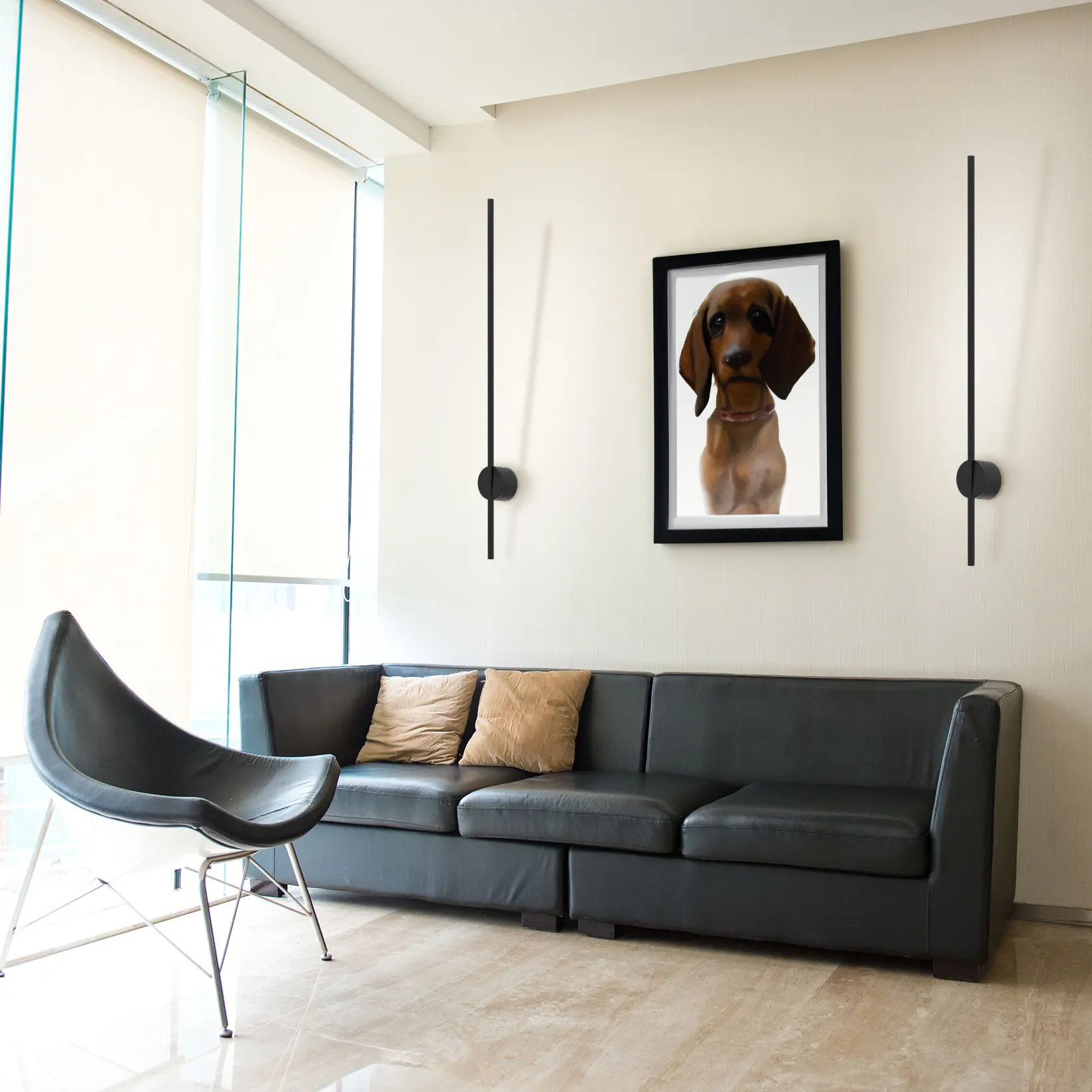 Kinkiet Chloe 85 w kolorze czarnym, z jedną diodą LED o mocy 11W i temperaturze barwowej 3000K. Zamontowany na ścianie, minimalistyczny design z prostokątnym źródłem światła oraz okrągłym mocowaniem. W tle widoczna kanapa i obraz.