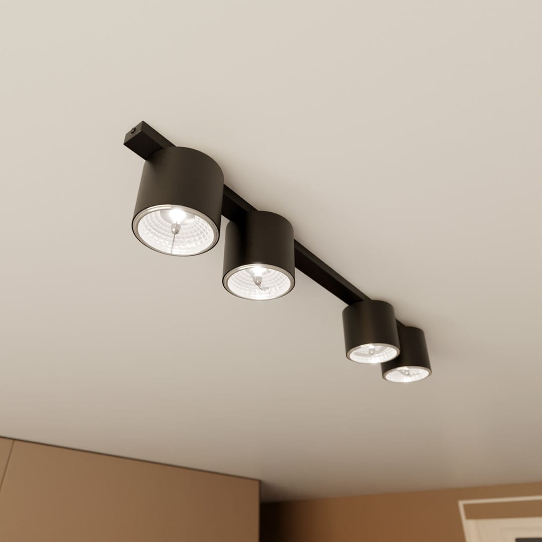 Czarna lampa sufitowa Nano z czterema oprawami GU10/AR 111, zamontowana na stropie, z cylindrycznymi kloszami w minimalistycznym stylu, emitującymi ciepłe światło. Ujęcie z dołu, ukazujące detale lampy i sufit.