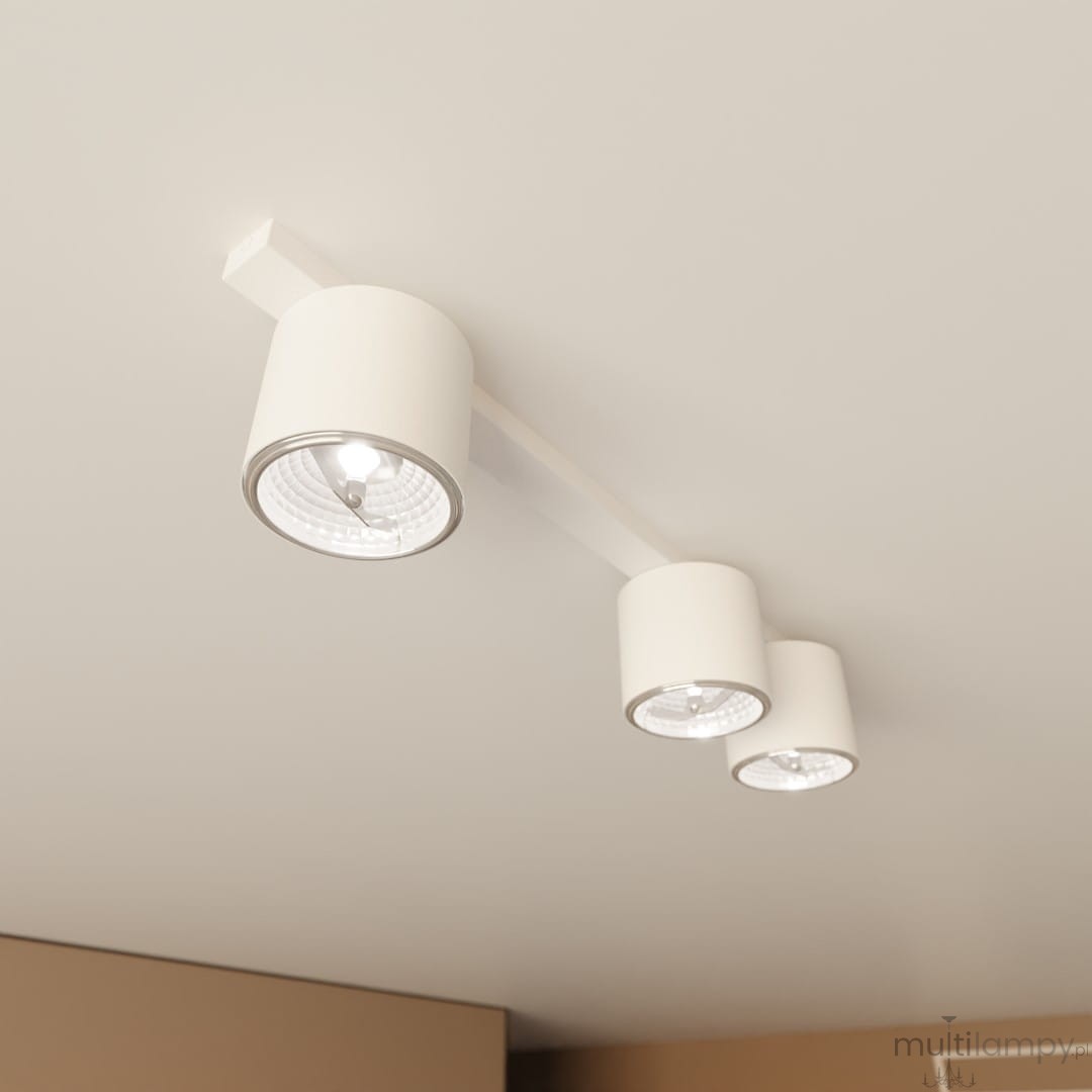 Biała lampa sufitowa z trzema źródłami światła GU10, zamontowana na prostokątnej podstawie. Klosze w formie cylindrów, z metalicznymi elementami, skierowane w różne strony. Minimalistyczny design, idealna do nowoczesnych wnętrz.