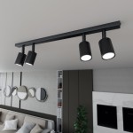 Czarna lampa sufitowa Flash z czterema reflektorami GU10, zamontowana na poziomej listwie. Reflektory mają cylindryczny kształt i emitują białe światło. Lampa umieszczona w nowoczesnym wnętrzu z sofą i dekoracyjnymi lustrami w tle.