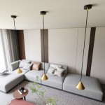 Lampa wisząca Elit 1xGX53 w kolorze czarnym i złotym, z minimalistycznym, stożkowym kloszem. Zawieszona na długim, czarnym przewodzie. Widoczna w nowoczesnym wnętrzu z szarym sofą i dekoracyjnymi poduszkami.