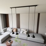 Lampa wisząca Elit 4xGX53 w kolorze czarnym, z czterema stożkowymi kloszami zawieszonymi na cienkich linkach, umieszczona nad szarym narożnikiem w nowoczesnym wnętrzu. Widoczne elementy otoczenia: szary dywan i stolik kawowy.