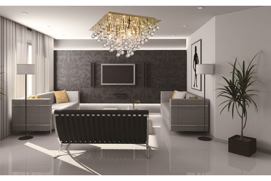 Lampa sufitowa Lancaster Crystal 5xE14 w kolorze złotym, z dekoracyjnymi kryształkami, zamontowana na suficie w nowoczesnym wnętrzu. Widoczne są również meble, telewizor oraz rośliny w aranżacji salonu.