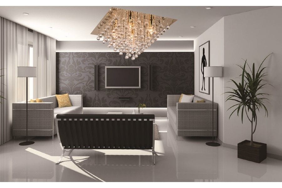 Lampa sufitowa Lancaster Crystal w kolorze złotym, z siedmioma miejscami na żarówki E14, w eleganckim, kryształowym designie. Zawieszona w nowoczesnym wnętrzu, nad sofą, w jasnym pomieszczeniu z ciemną tapetą w tle.
