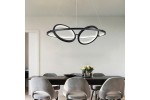 Czarna lampa wisząca Gilian z trzema źródłami LED 40W, o nowoczesnym, owalnym kształcie, zawieszona nad stołem w jadalni. W tle widoczna drewniana ściana oraz szare krzesła. Lampa ma subtelną, matową powierzchnię.