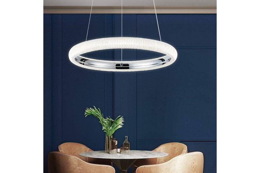 Lampa wisząca Vigo 1xLED/18W w chromowanej oprawie, okrągła, z dekoracyjnym pierścieniem świecącym na biało. Zawieszona nad okrągłym stołem w eleganckim wnętrzu, na tle granatowej ściany.